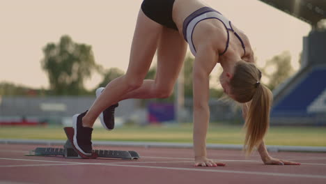 Sportlerin-Startet-Ihren-Sprint-Auf-Einer-Laufstrecke.-Läufer-Startet-Aus-Den-Startblöcken-Auf-Der-Laufstrecke.-Junge-Sportlerin-Beginnt-Vom-Block-Aus-Zu-Laufen.-Zeitlupe